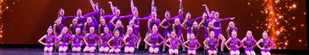 Dancers posing in purple costumes on stage