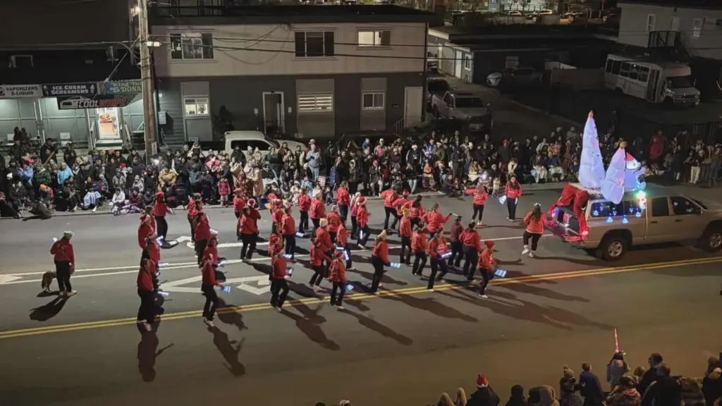 Dancers dancing in a parade walking behind a truck