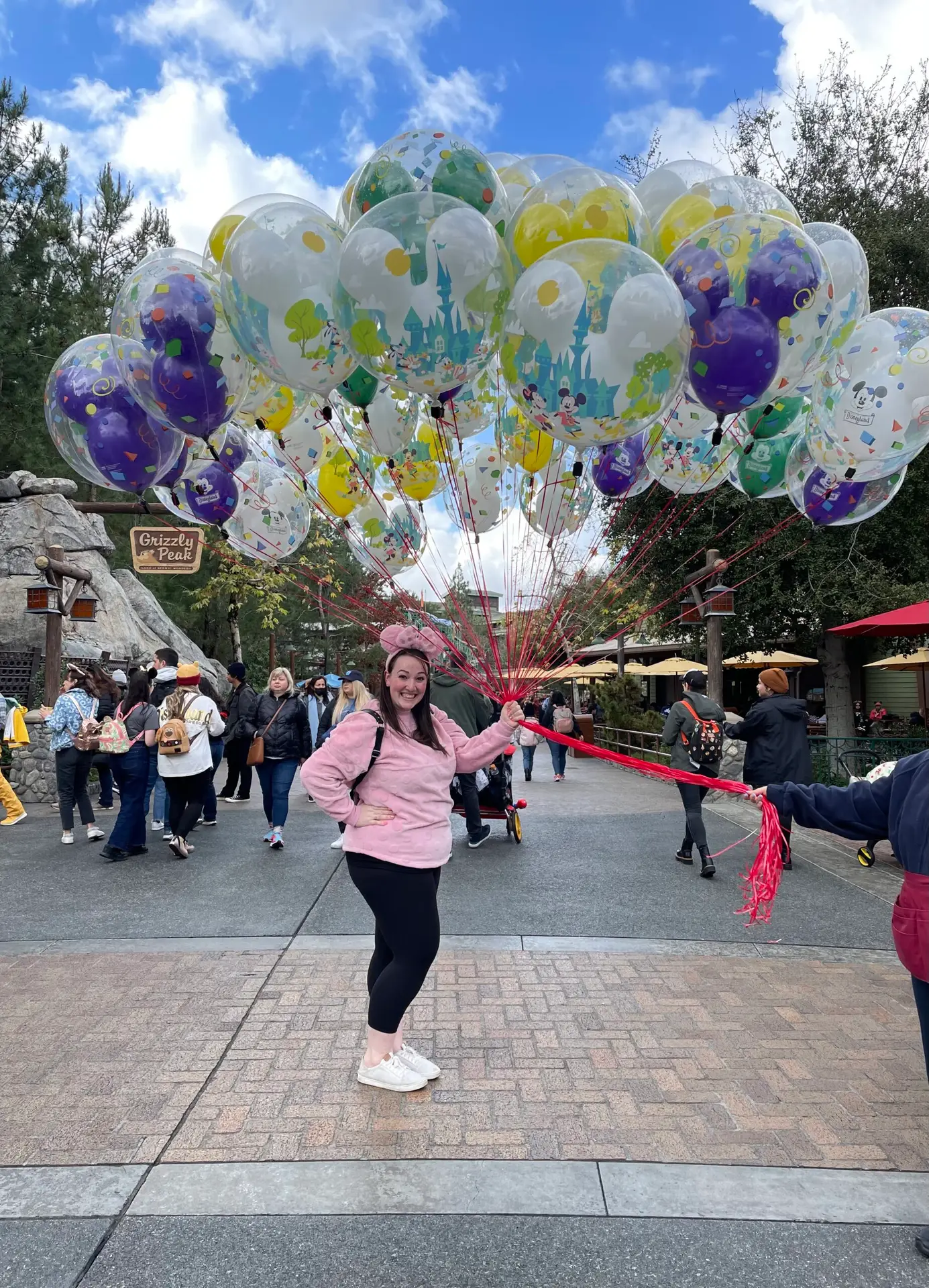 Female standing holding Mickey Mouse balloons