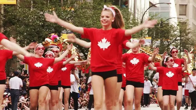 dancers wearing red canada shirts dancing up the street